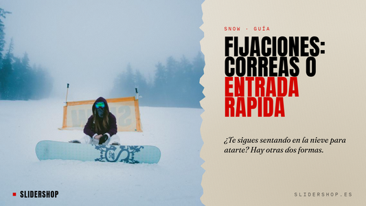 Snowboarder sentada en la nieve con la tabla delante, a punto de atarse las fijaciones